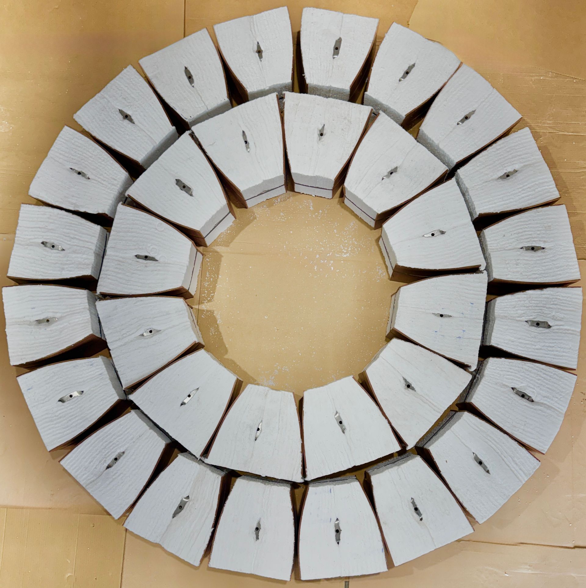 White, triangular packaged item held together with black straps. One side shows brown, layered material.