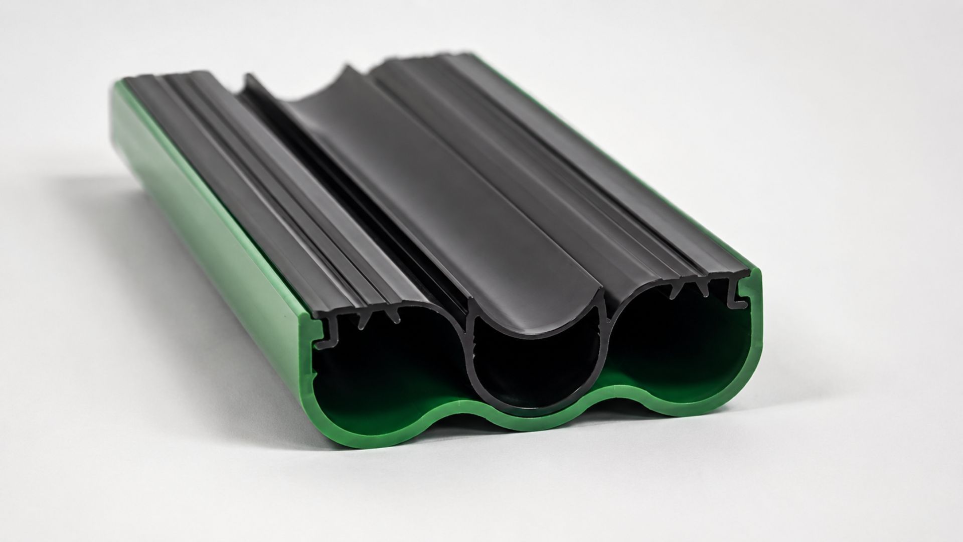 Black and green rubber floor threshold strip with grooved channels on a white background