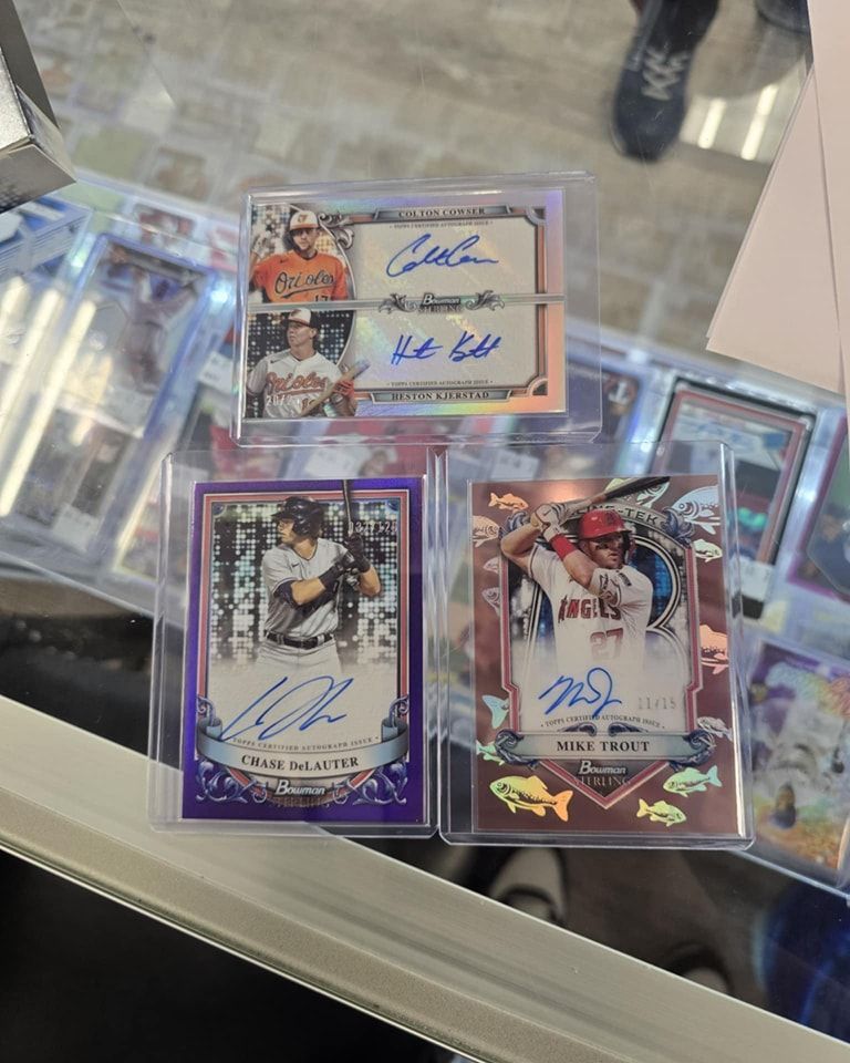Three baseball cards with signatures on them are sitting on a table.