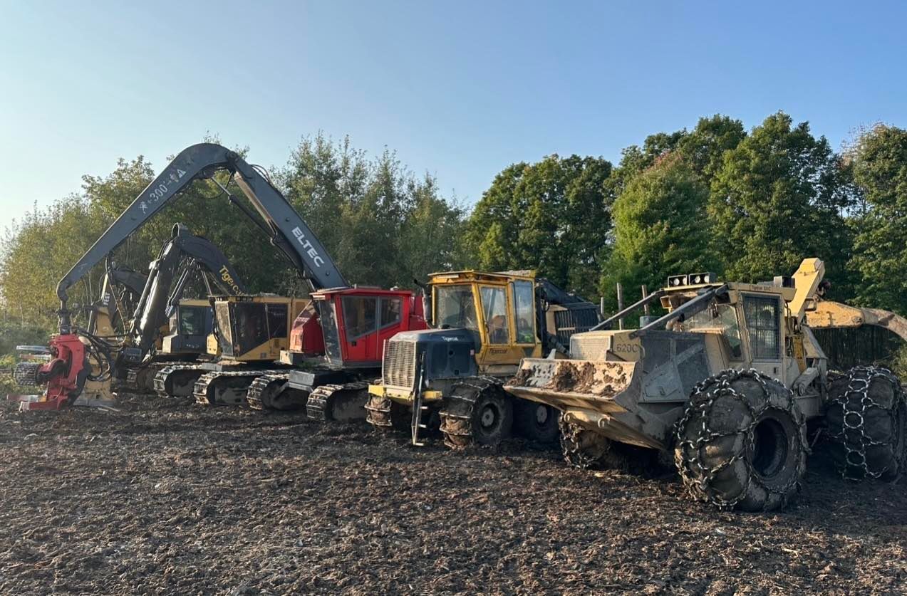Un groupe de véhicules de construction est garé dans un champ de terre.