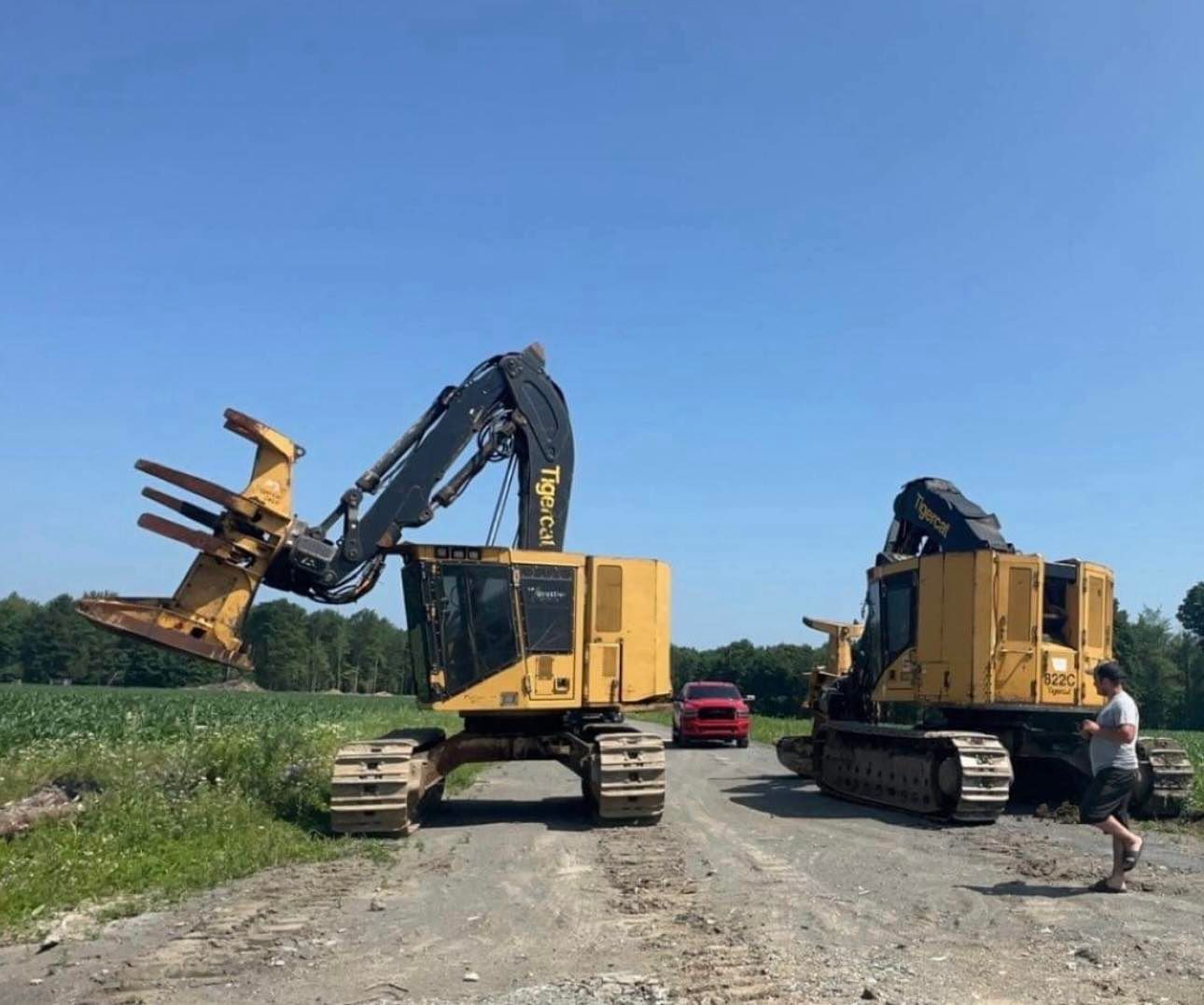 Deux bulldozers sont garés au bord d'un chemin de terre.