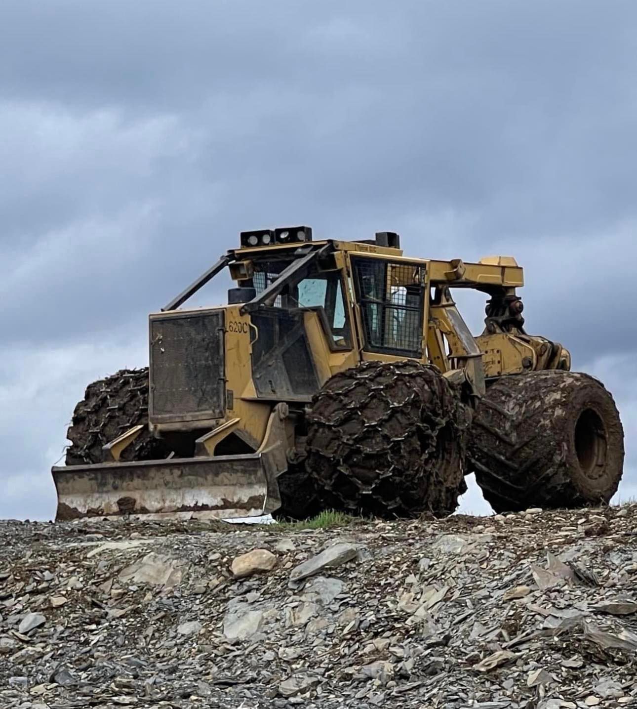 Un bulldozer est garé au sommet d'une colline rocheuse.