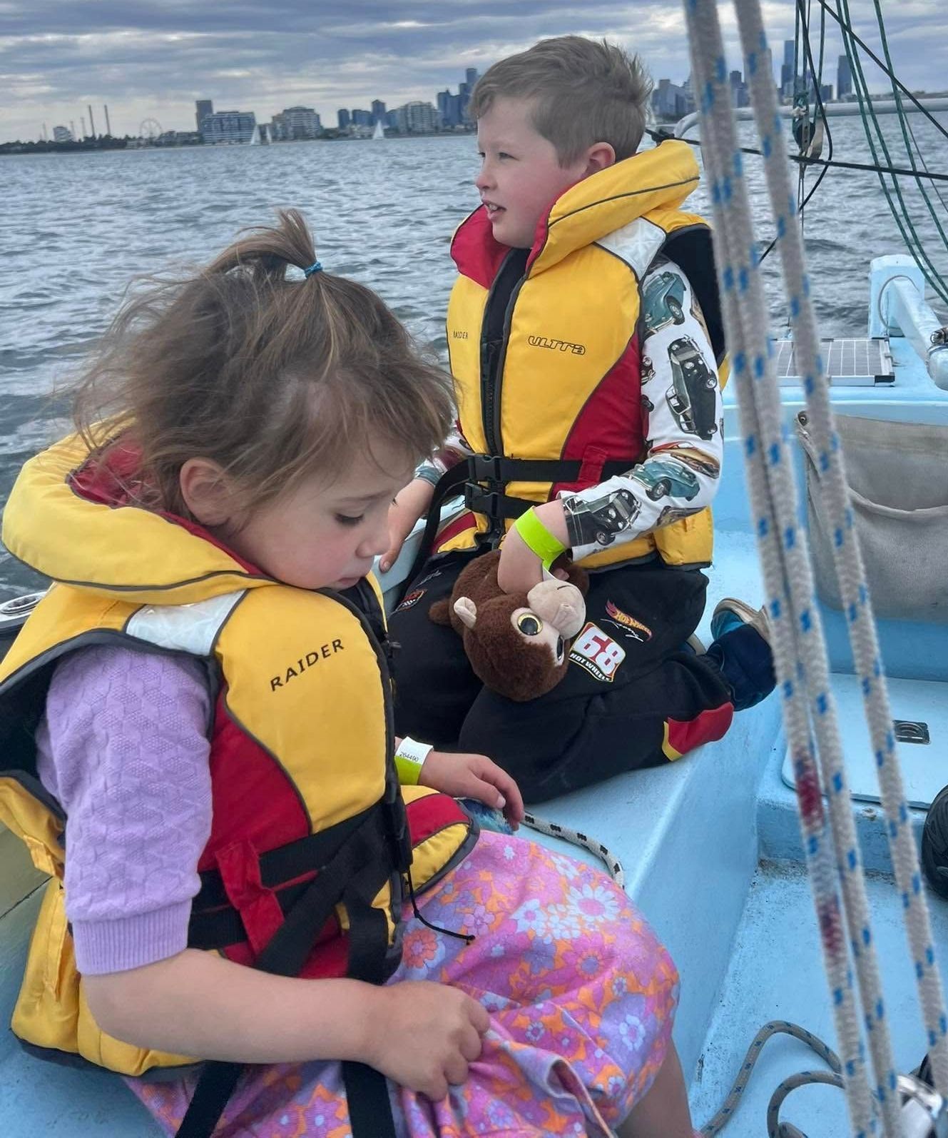 A boy and a girl are sitting on a boat wearing life jackets