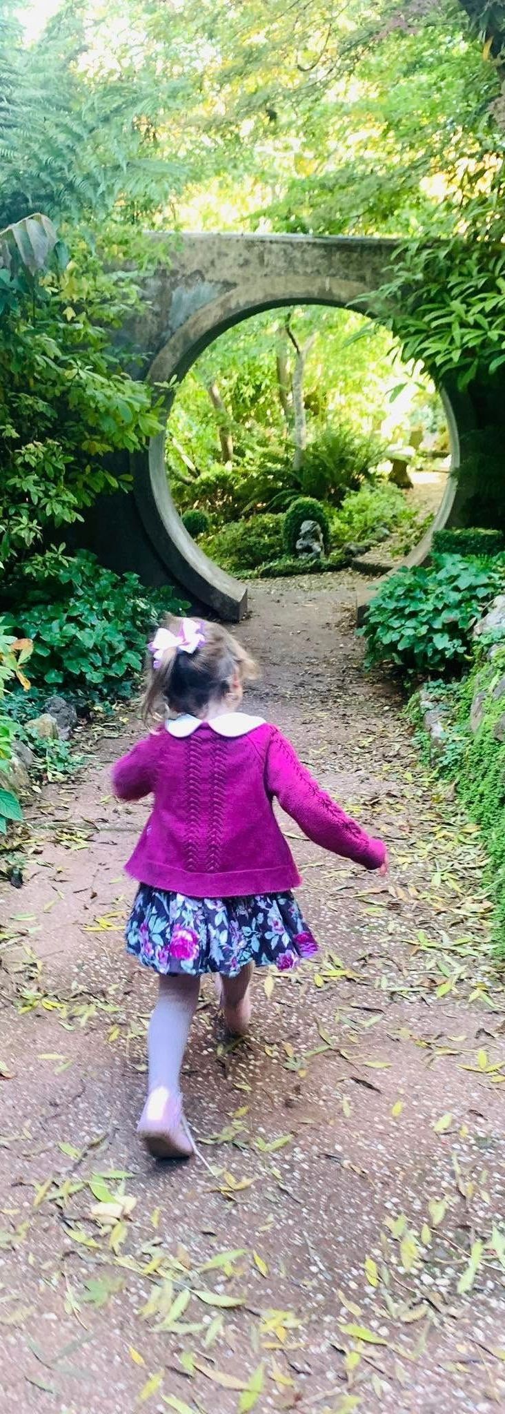 A little girl is running down a path in a park.
