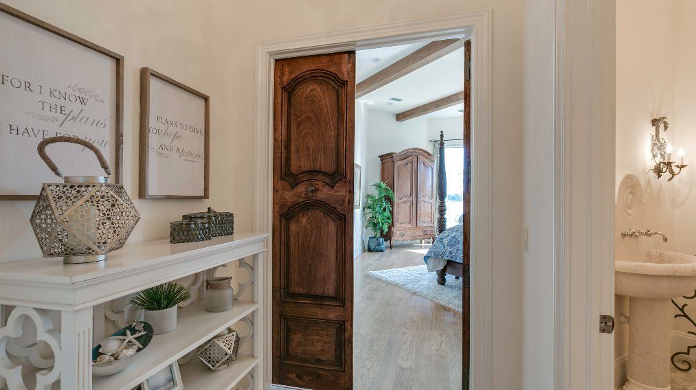 A hallway with a wooden door leading to a bathroom.