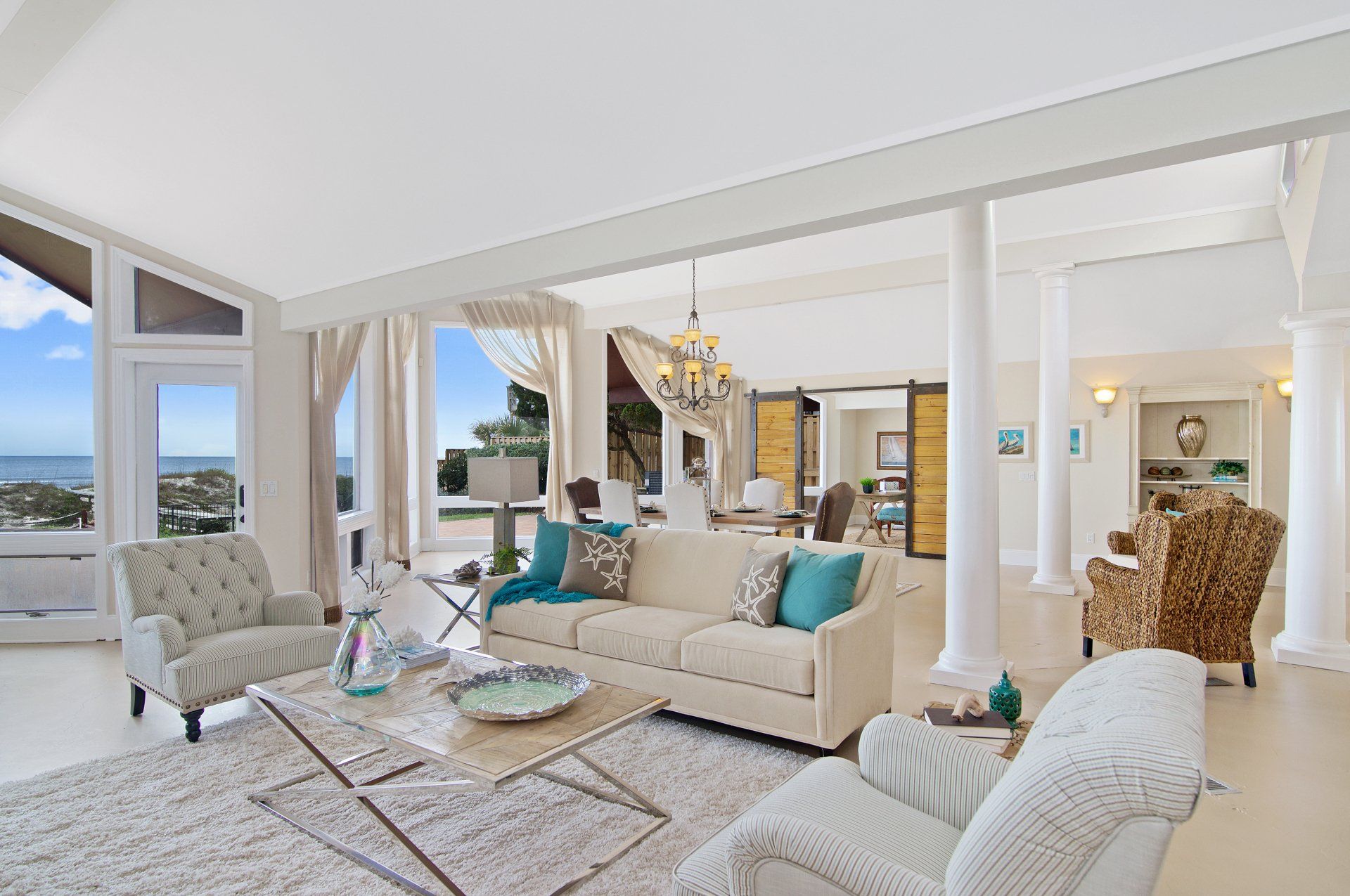 A living room with a couch , chairs , a coffee table and a view of the ocean.