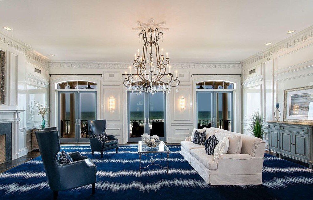 A living room with a couch , chairs , and a chandelier.
