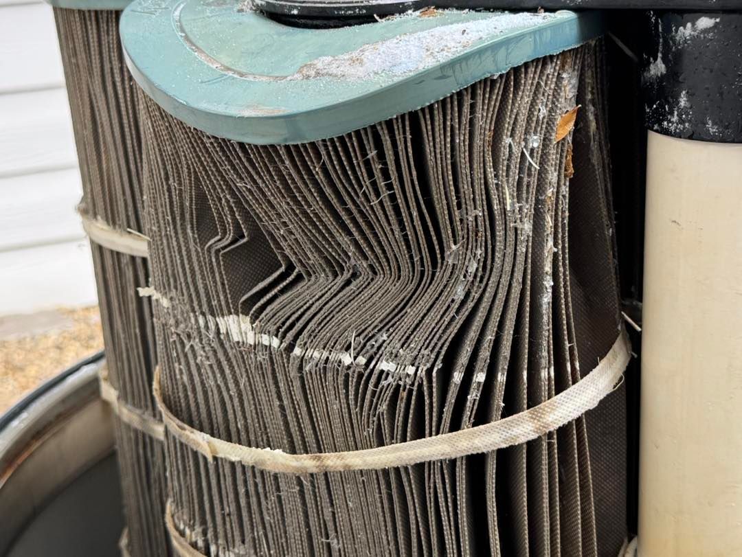 A dirty, damaged swimming pool cartridge filter with buckled and torn pleated fabric panels held by white plastic straps.