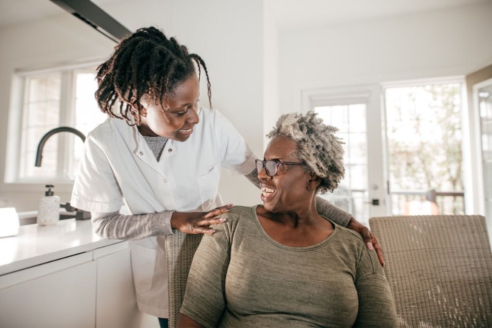 A nurse is talking to an elderly woman who is sitting in a chair.