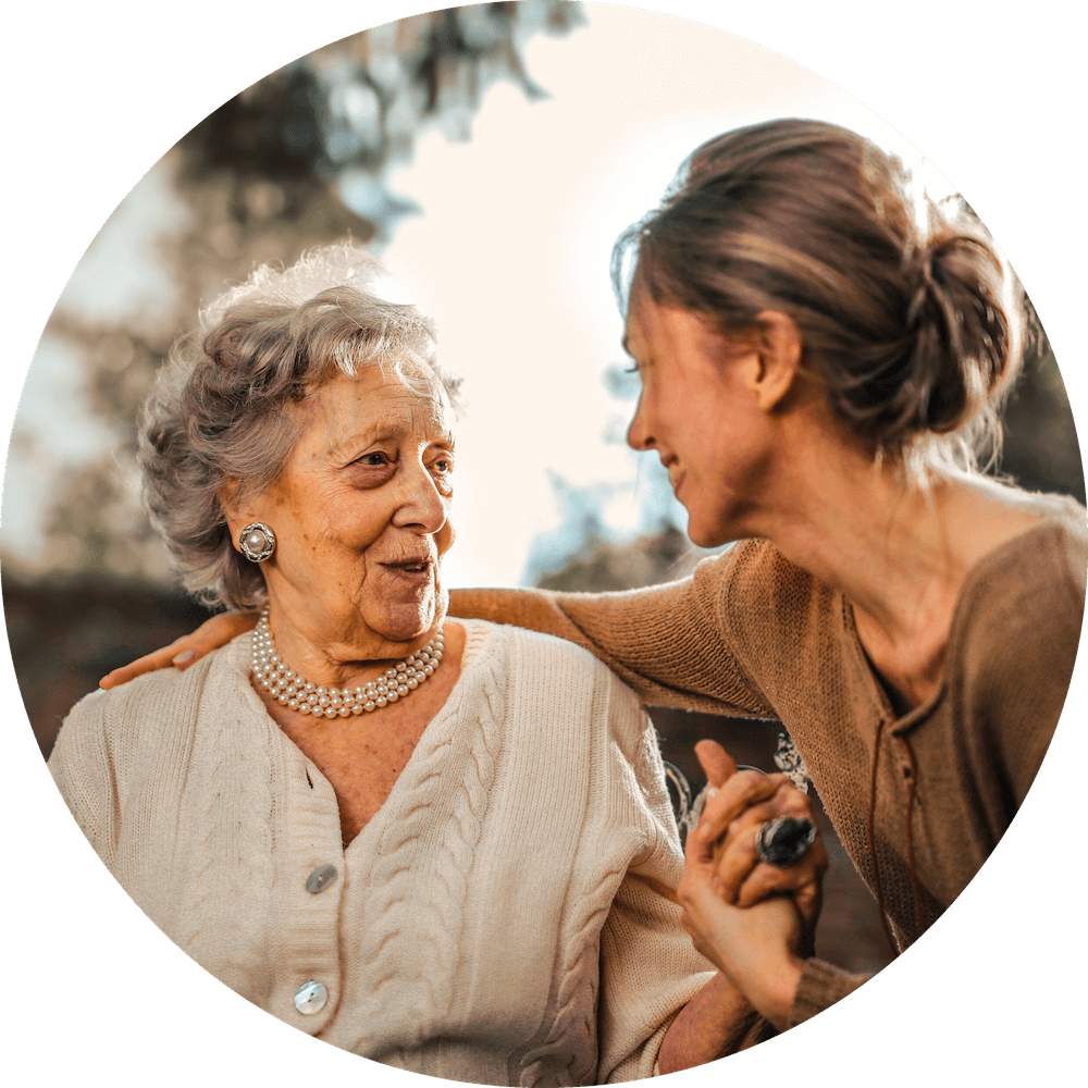 A woman is talking to an older woman in a wheelchair.