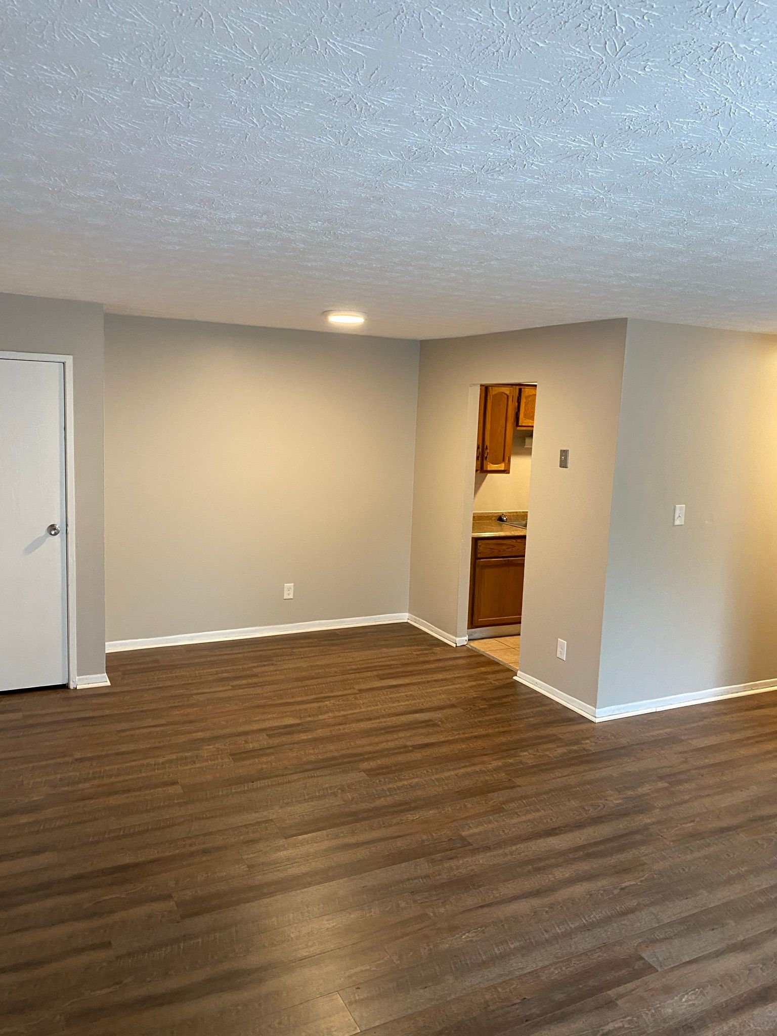 Yearling Court Apartments - Living room with hardwood floor with kitchen door