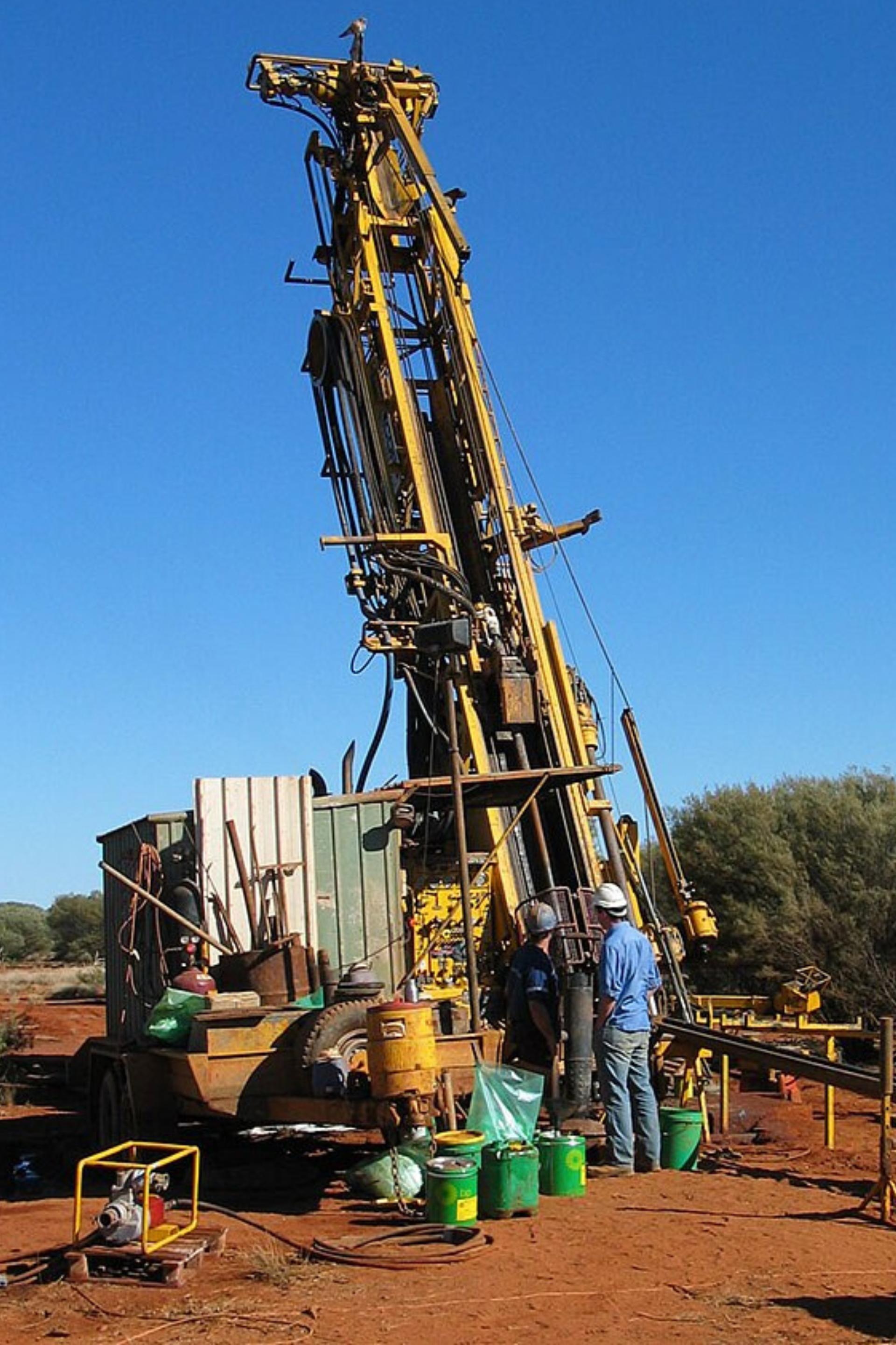 A large yellow crane is being used to drill a hole in the ground
