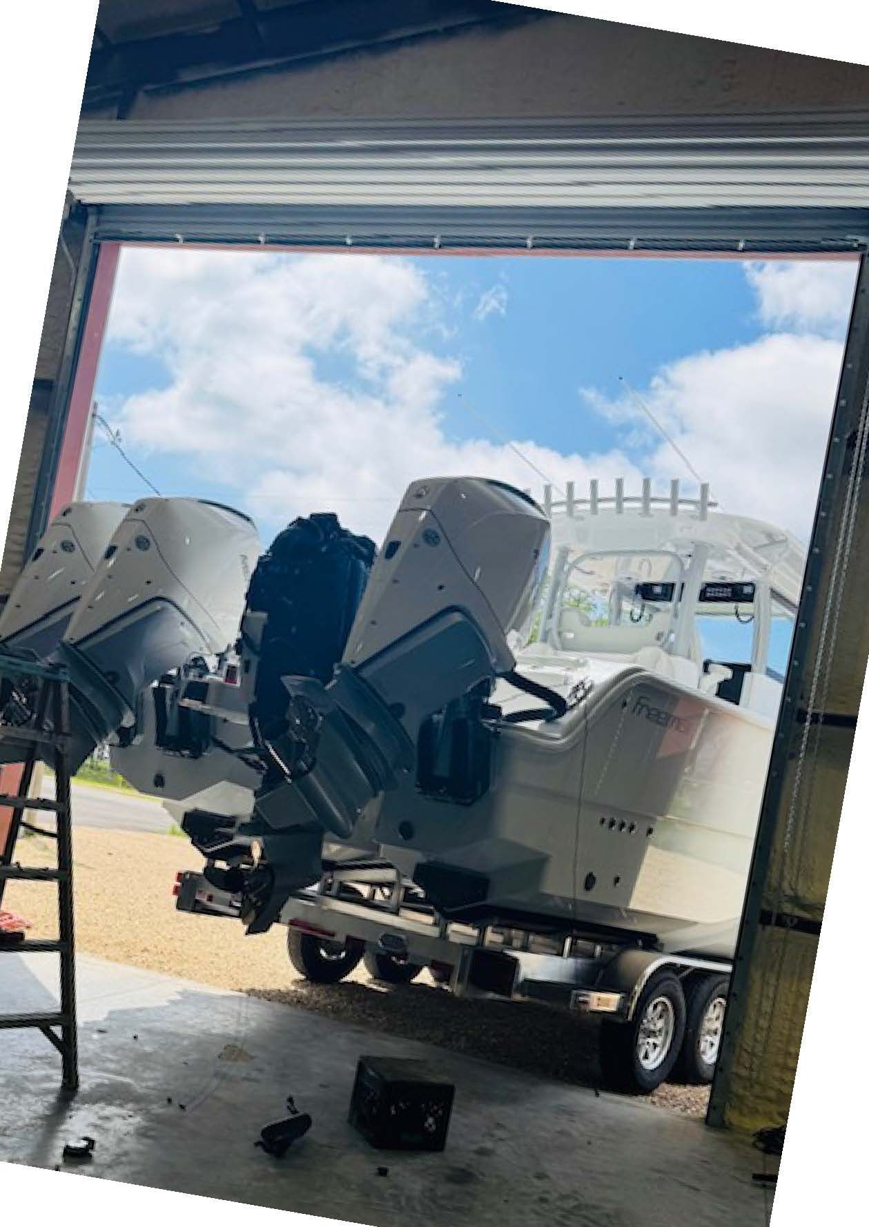 A white boat is parked on the side of the road in front of trees.