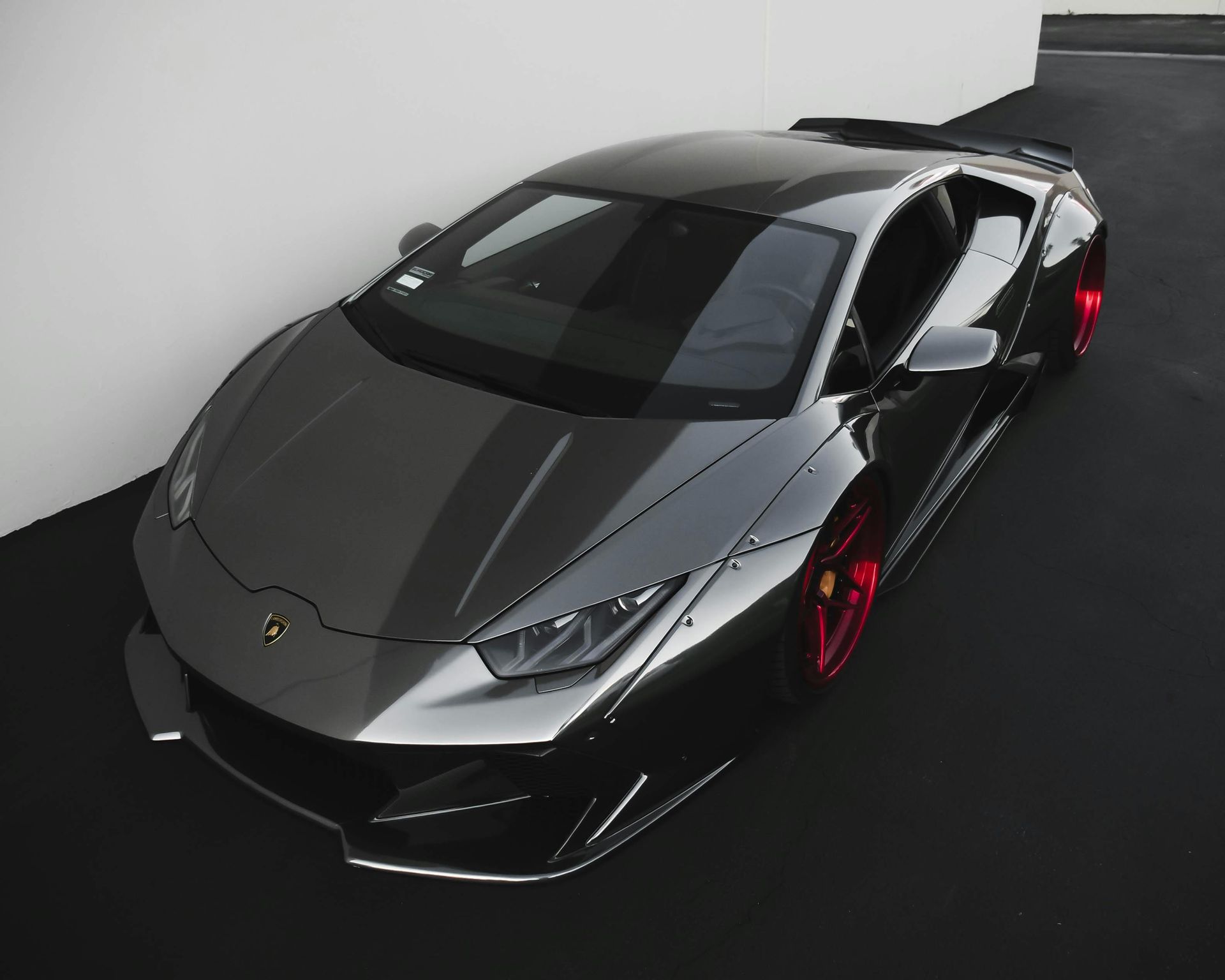 Gray Lamborghini sports car with red wheels parked indoors.