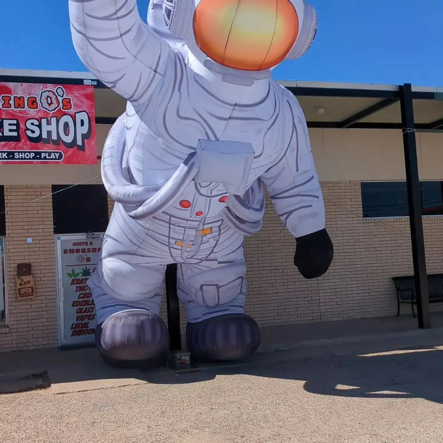 A giant inflatable astronaut is standing in front of a store called the shop