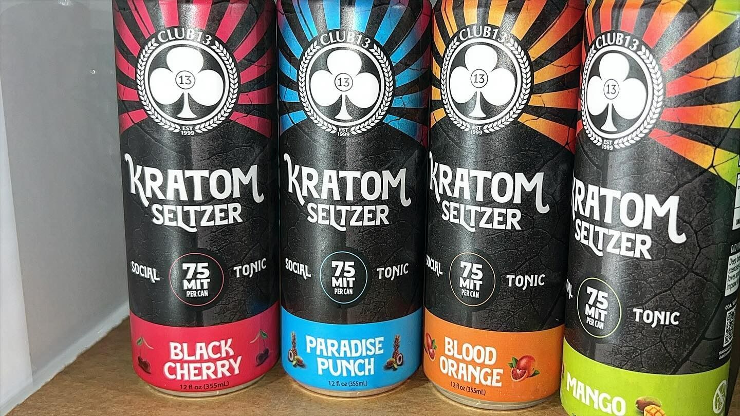 Four cans of kratom seltzer are sitting on a wooden table.