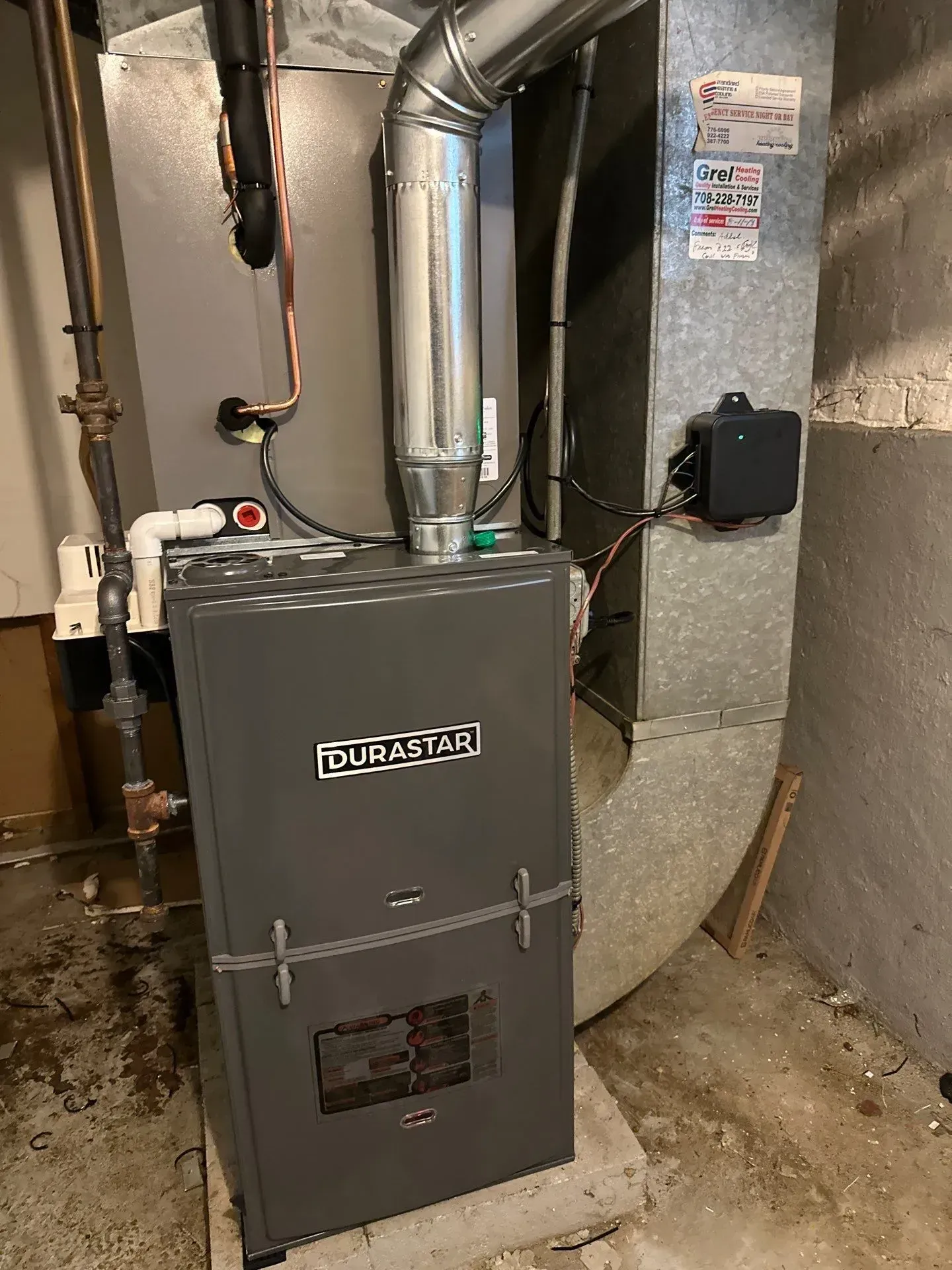 A natural gas furnace in a basement setting with ductwork and venting. Gray furnace with the brand 