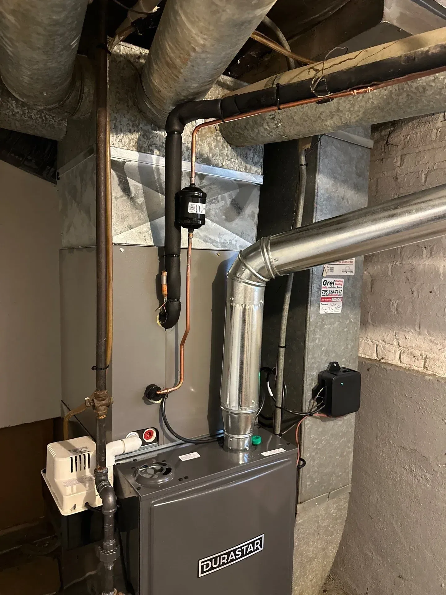Furnace system in a basement with pipes, ductwork, and a control panel.