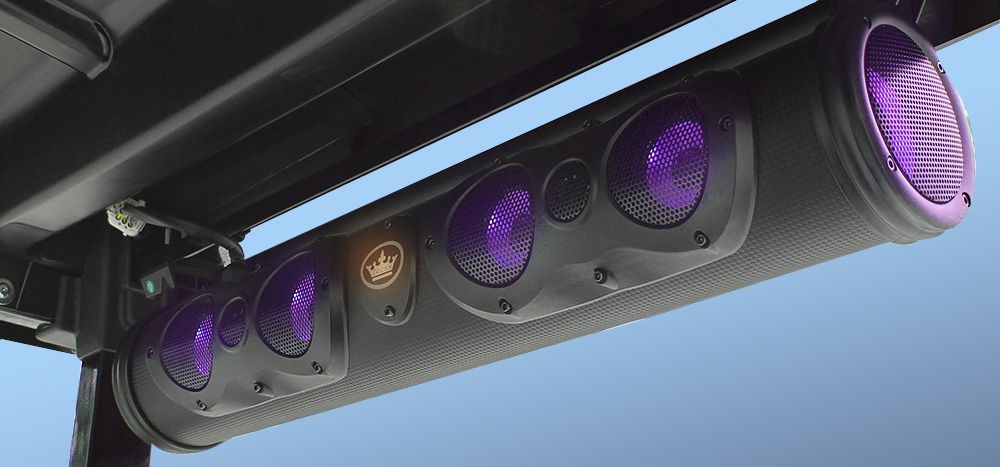A black speaker system with purple lights attached to a black structure against a blue sky.