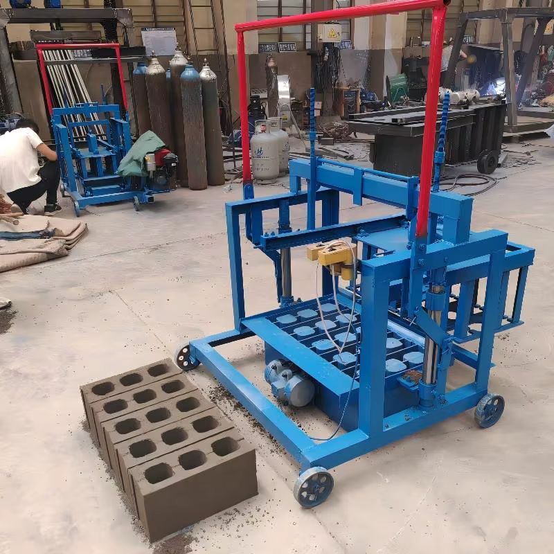 Blue block-making machine in a workshop beside freshly molded concrete blocks