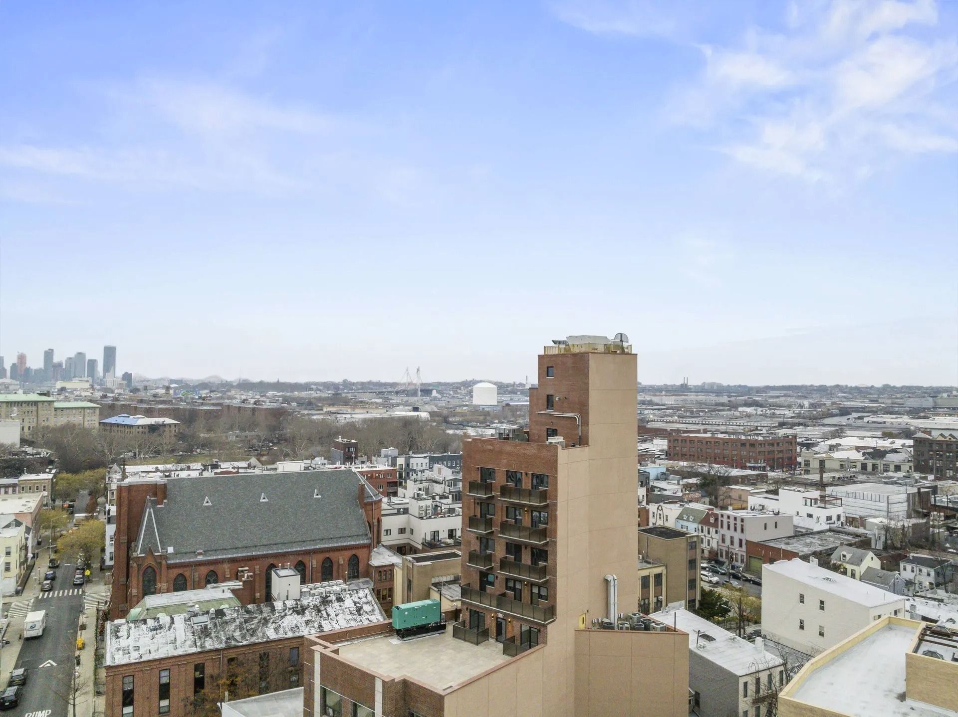 City skyline with apartment buildings under a cloudy blue sky, viewed from above