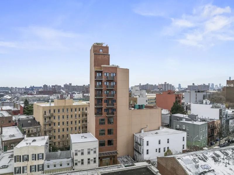 Snowy cityscape with mid-rise apartment buildings under a partly cloudy sky