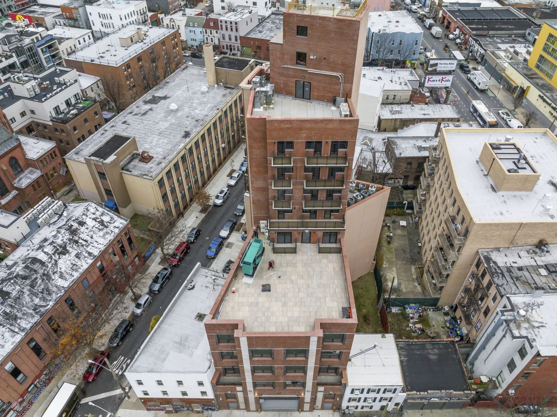 Aerial view of a snowy urban block with brick apartment buildings and narrow streets