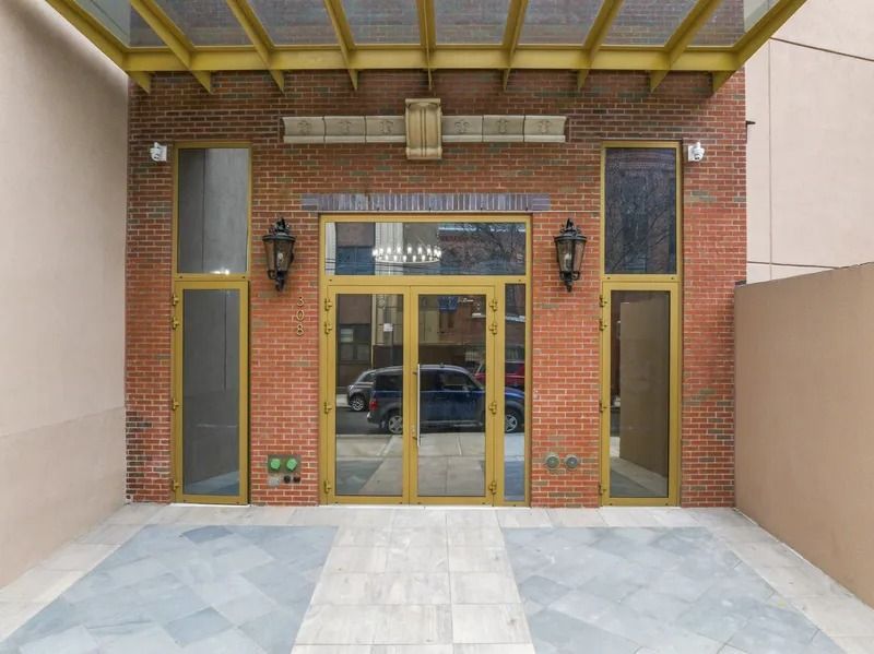 Brick building entrance with gold-framed glass doors and windows under a covered awning