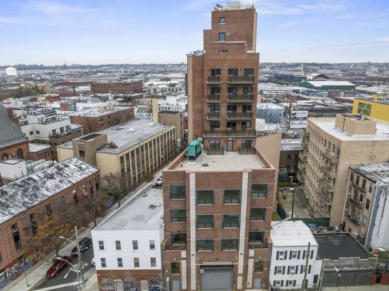 Snow-covered city skyline with a tall brick building centered among lower urban buildings.