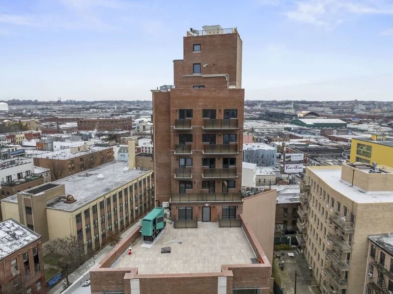 Snowy city skyline with a tall brick building centered between shorter rooftops.