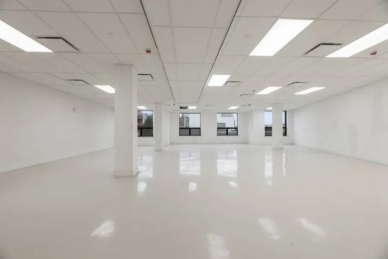 Bright empty office space with white floors, walls, pillars, and ceiling lights