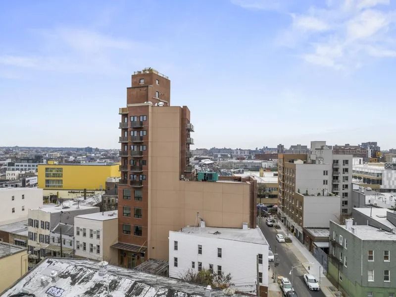 Snowy cityscape with a tall brown apartment building under a clear blue sky