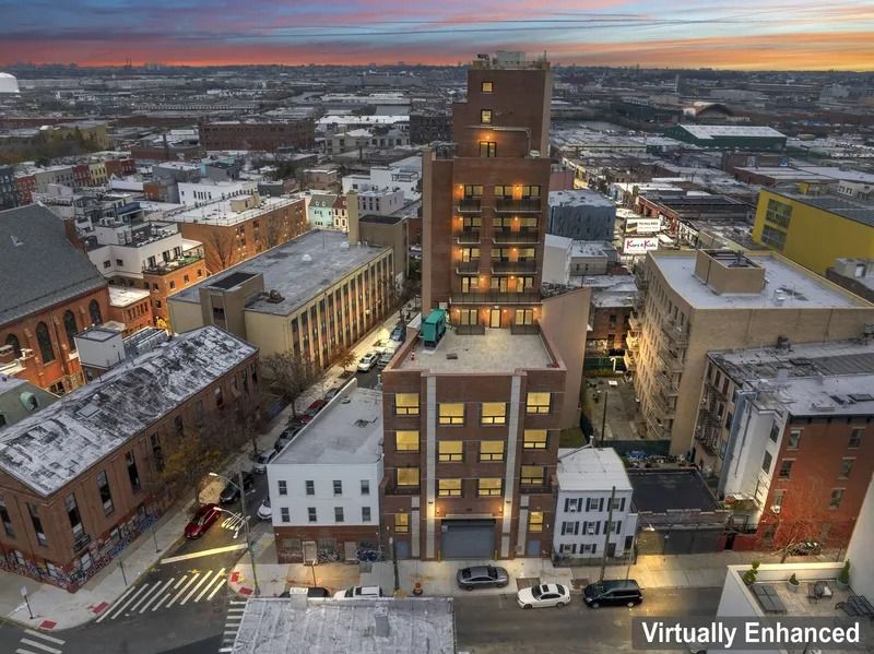 Snowy downtown skyline at dusk with a tall brick building centered among low-rise buildings.
