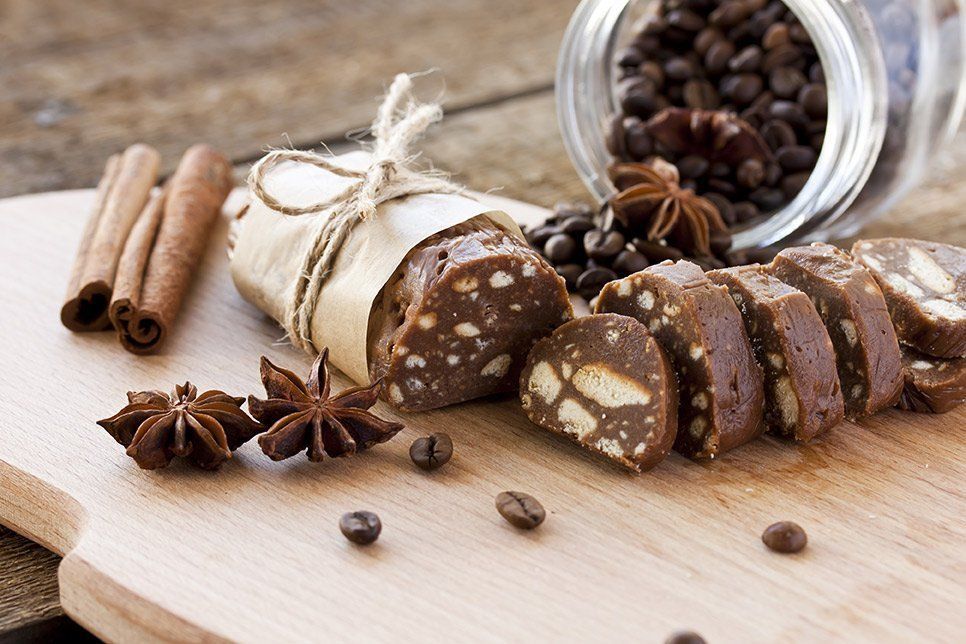 Sliced chocolate biscotti with nuts, cinnamon sticks, star anise, and coffee beans on a wooden board