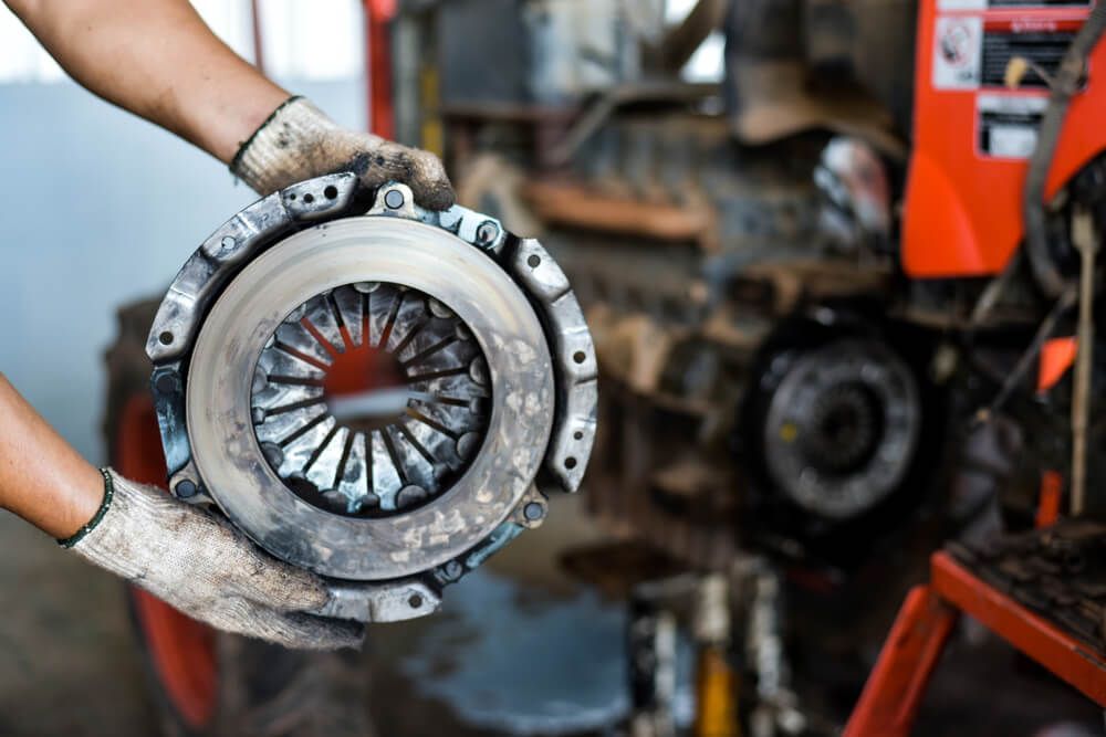 A Man Is Holding A Clutch Plate In His Hands — Zappala Motors in Bungalow, QLD