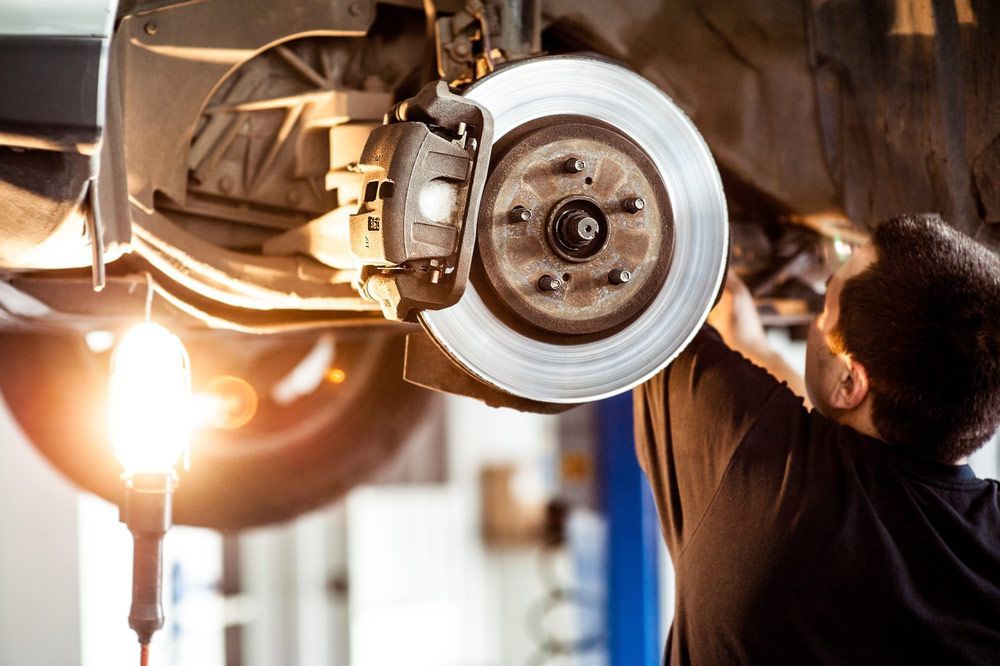A Man is Working on the Brake System of a Car in a Garage — Zappala Motors in Bungalow, QLD