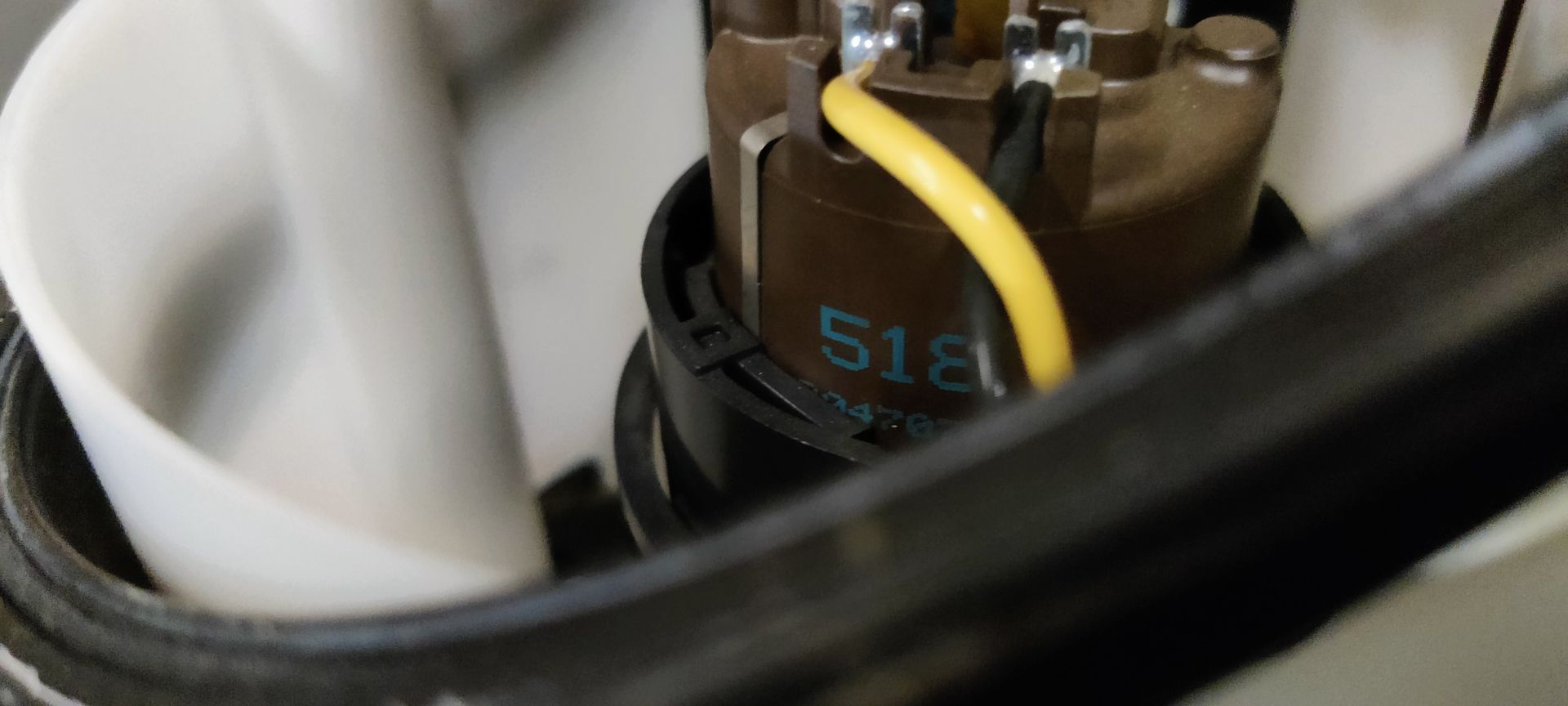 Een brandstofpompunit voor auto's met een blauwe ronde dop, een wit plastic reservoir en een zwarte vlottersensor.