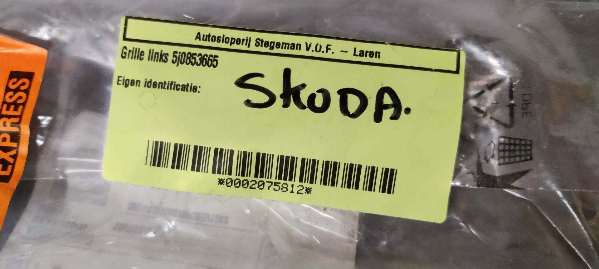 Zwarte kunststof bumper met mistlampgrille, ronde lampbehuizing en horizontale lamellen, geplaatst tegen een betonnen vloer.