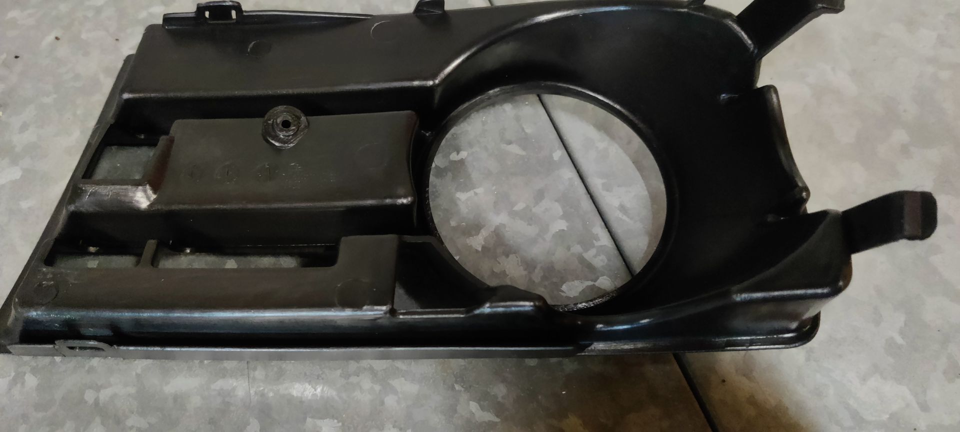 Een zwarte plastic afdekking voor de mistlampgrille van de voorbumper van een auto.