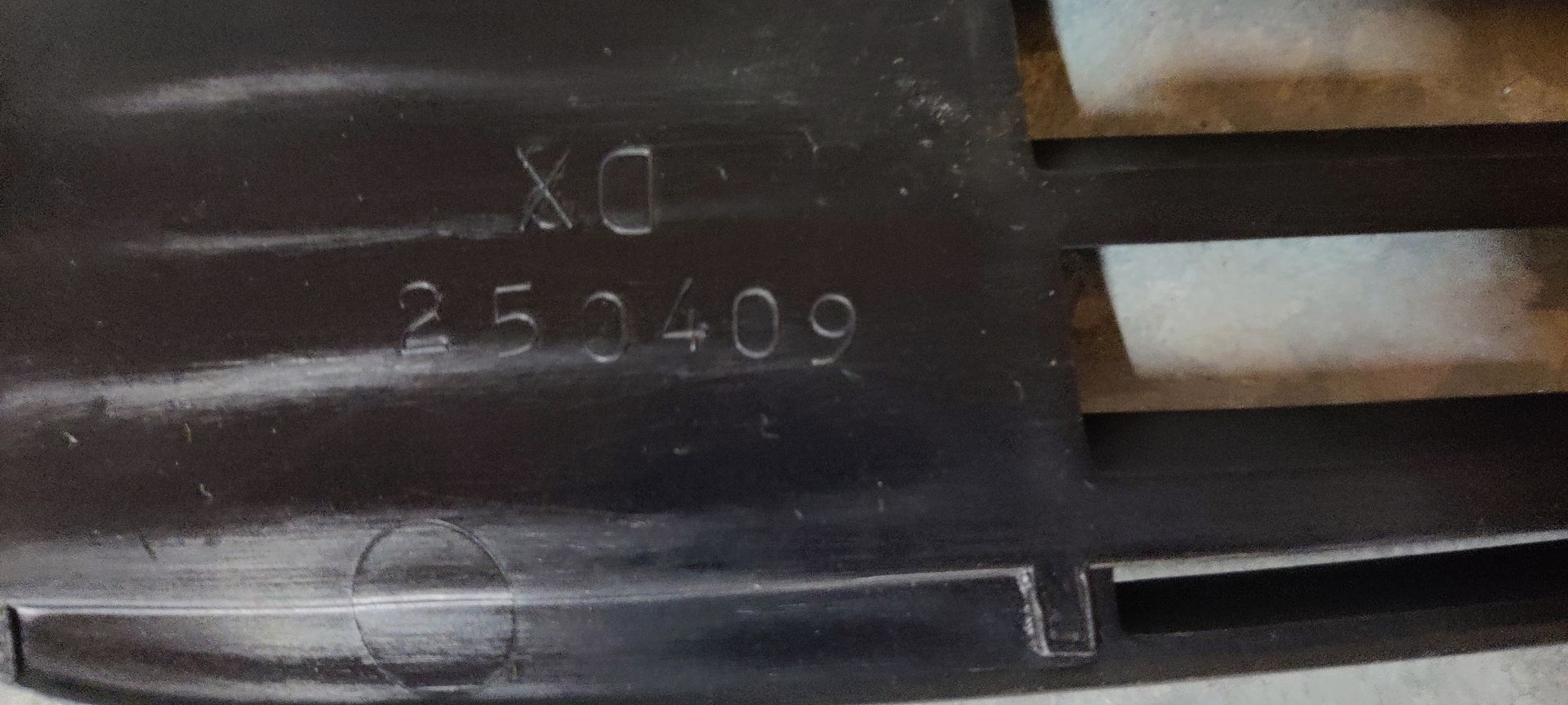 Een zwart, rechthoekig grille van kunststof voor autobumpers, met drie horizontale lamellen en een ronde uitsparing voor een sensor aan één kant.