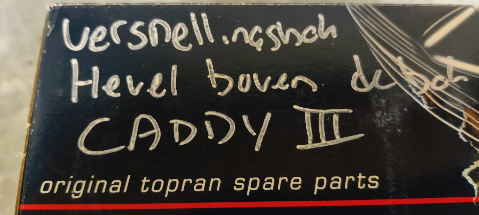 Een metalen spanarm voor auto's met een spiraalveer, geplaatst voor de originele blauwe doos van het merk Toptul.