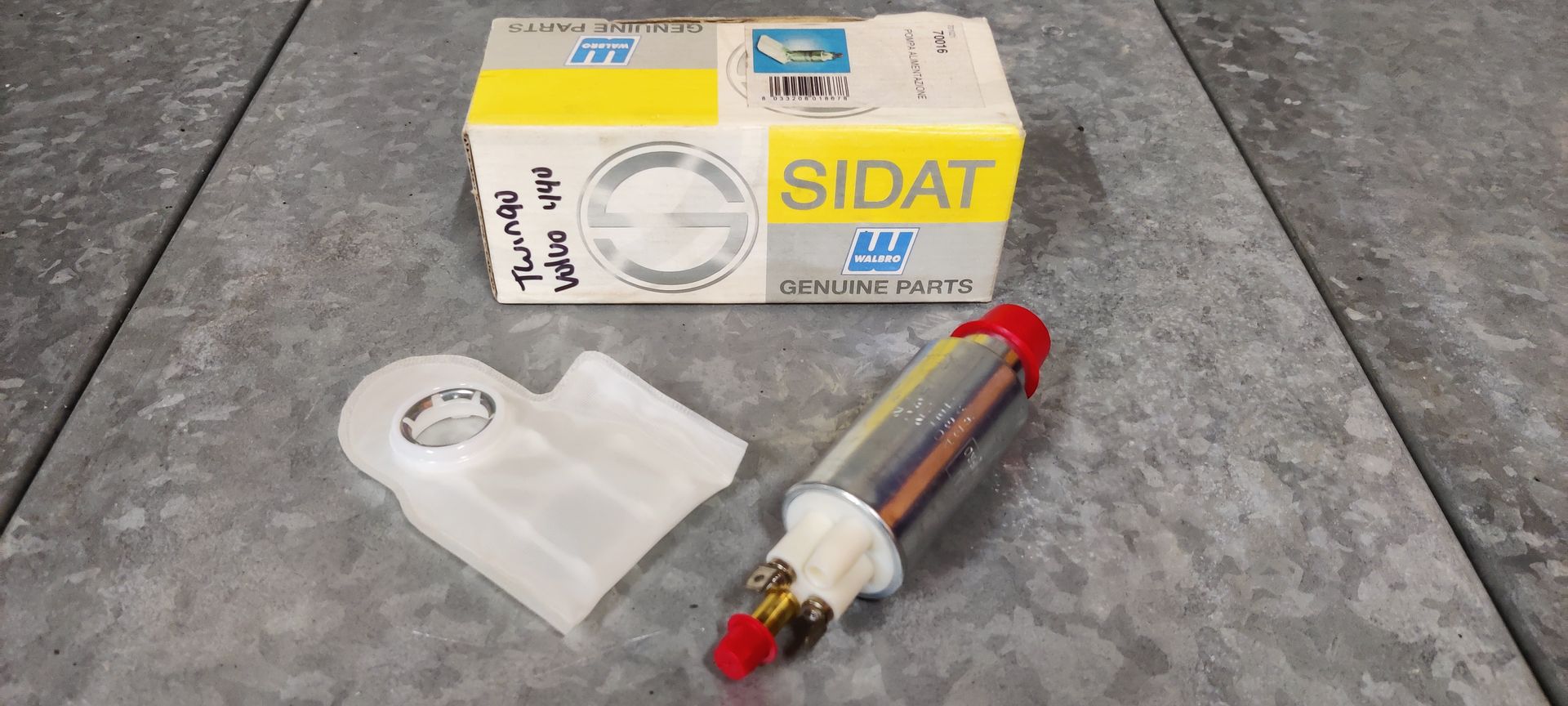 Een brandstofpomp en -filter voor auto's in een Sidat-behuizing op een grijze ondergrond.