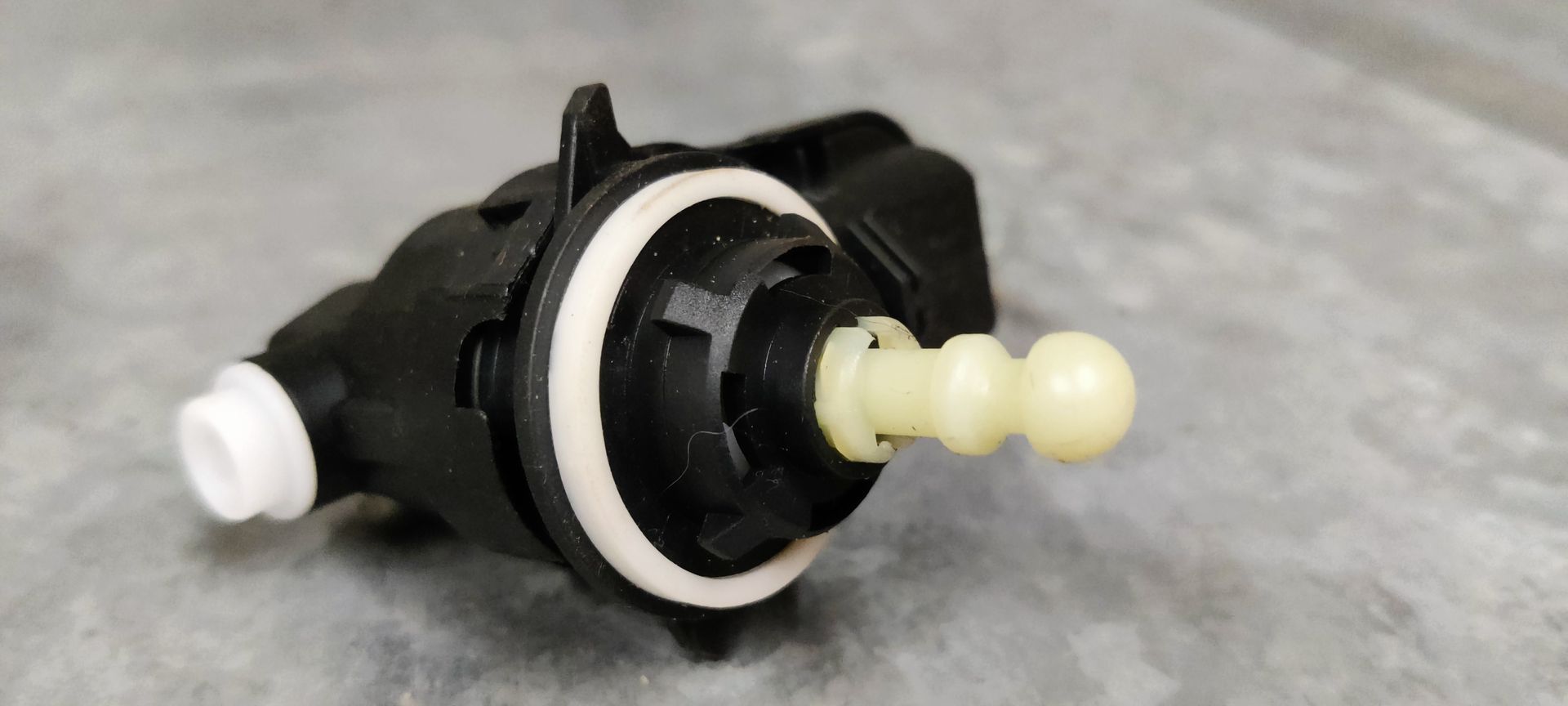 Een nieuw Citroën-onderdeel in een kartonnen doos naast een zwarte elektrische actuatormotor op een grijze ondergrond.