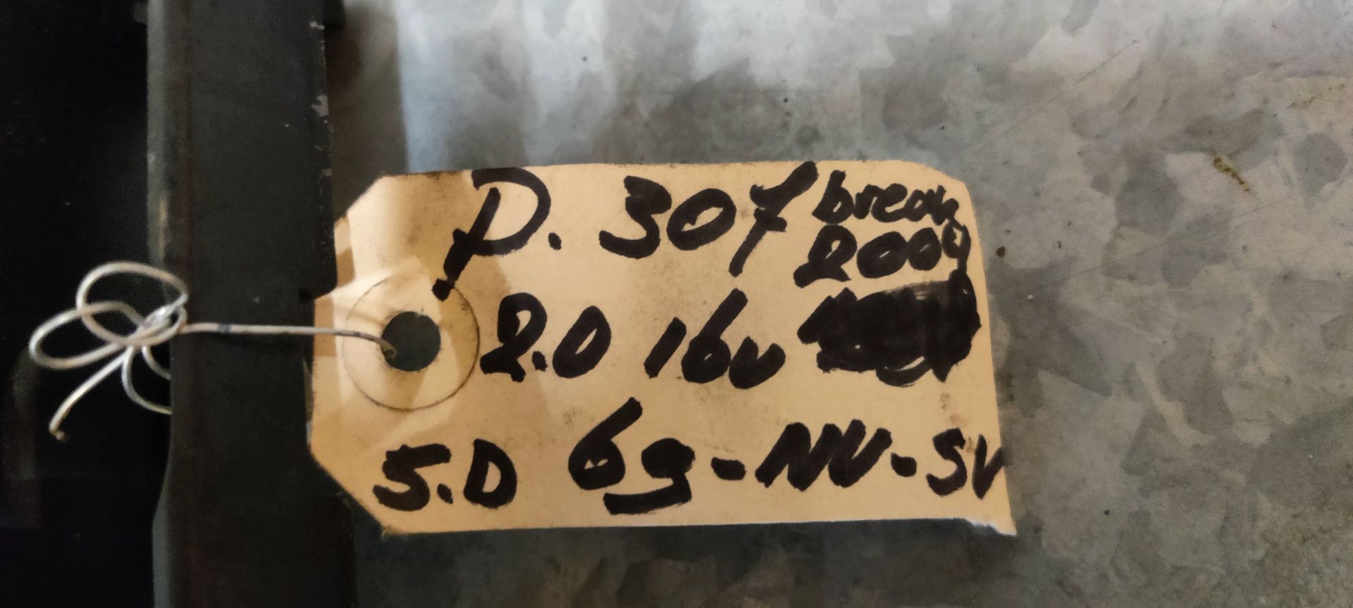 Een zekeringkast in een auto met diverse gekleurde zekeringen en meerdere zwarte elektrische aansluitingen op een betegelde ondergrond.