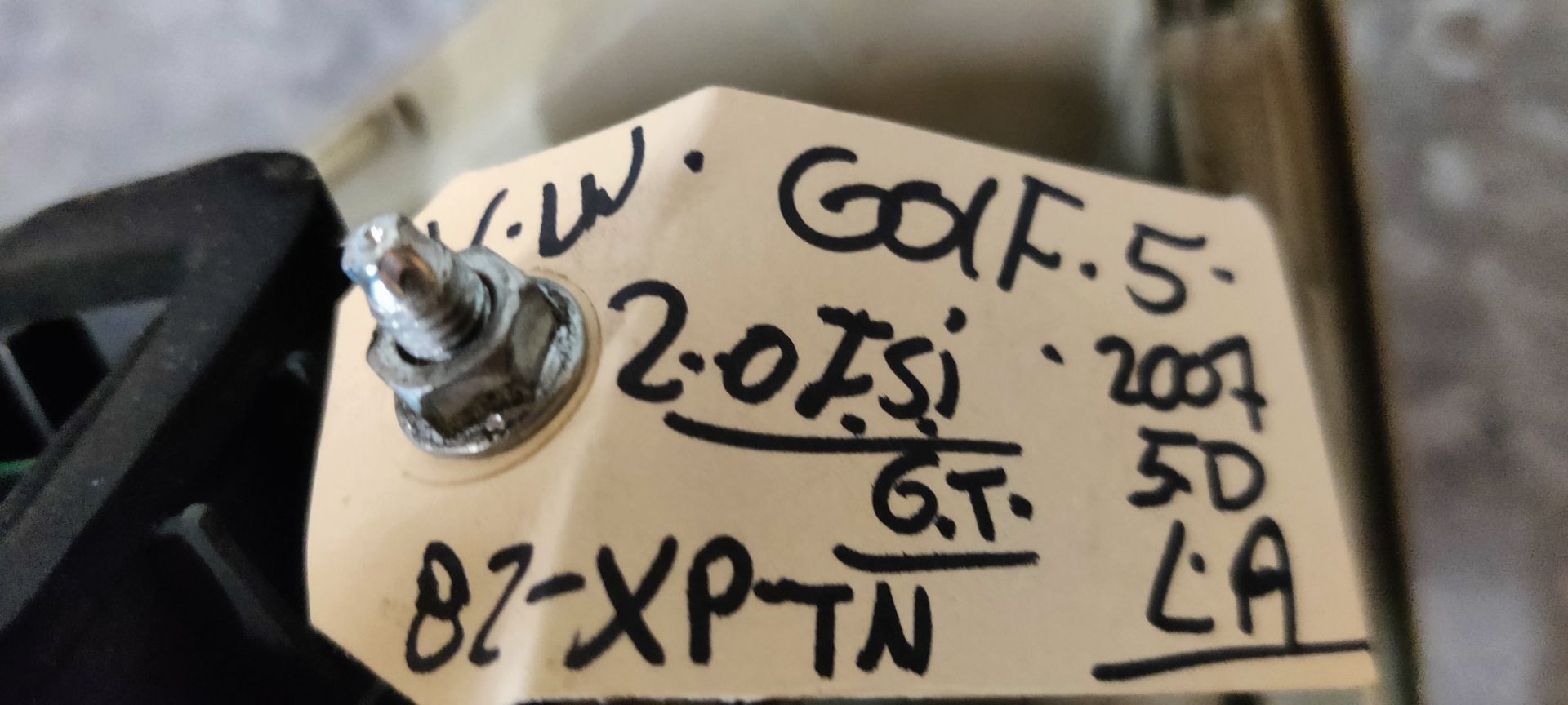 Een rode, driehoekige achterlichtunit voor auto's, met een ronde centrale lens, rustend op een grijs betegeld oppervlak.