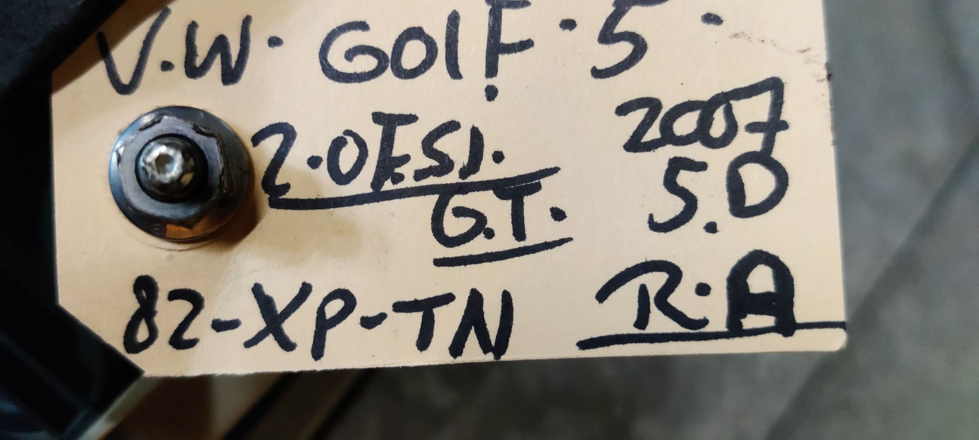 Een rode autoachterlichtunit met een ronde, witte lens voor het achteruitrijlicht in het midden, tegen een grijze achtergrond.