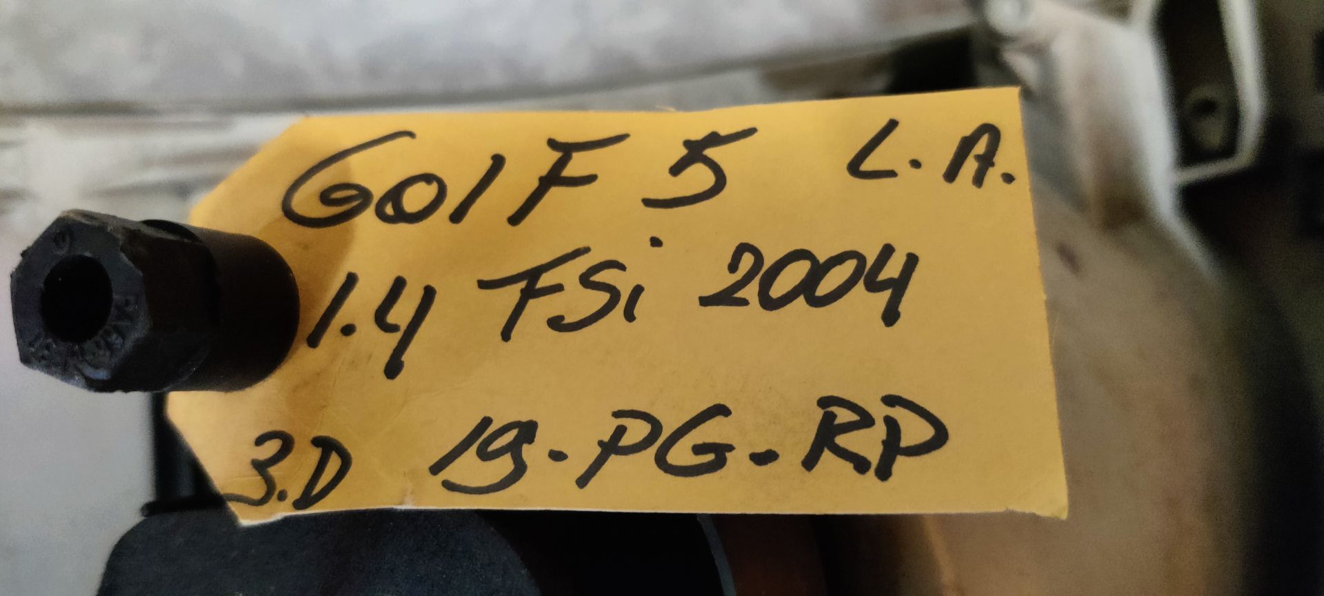 Een rode, driehoekige achterlichtunit voor auto's met een ronde centrale lens, rustend op een grijze ondergrond.