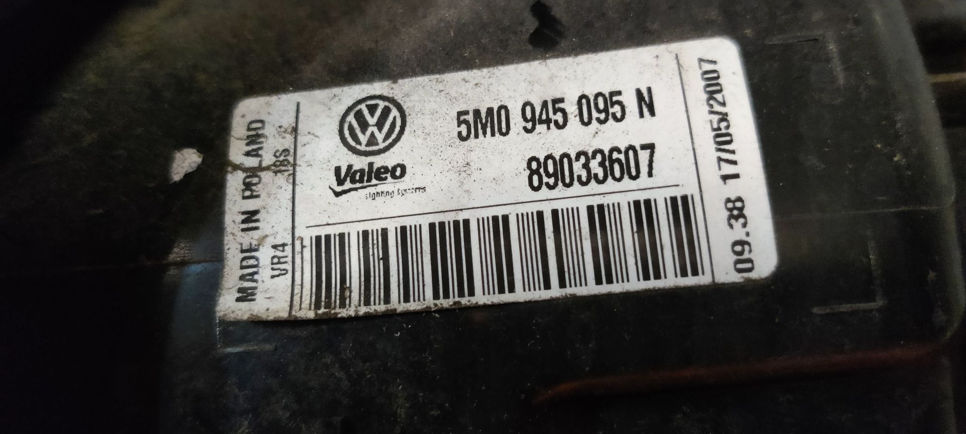 Een rode en transparante achterlichtunit van een auto, rustend op een grijze betonnen ondergrond.