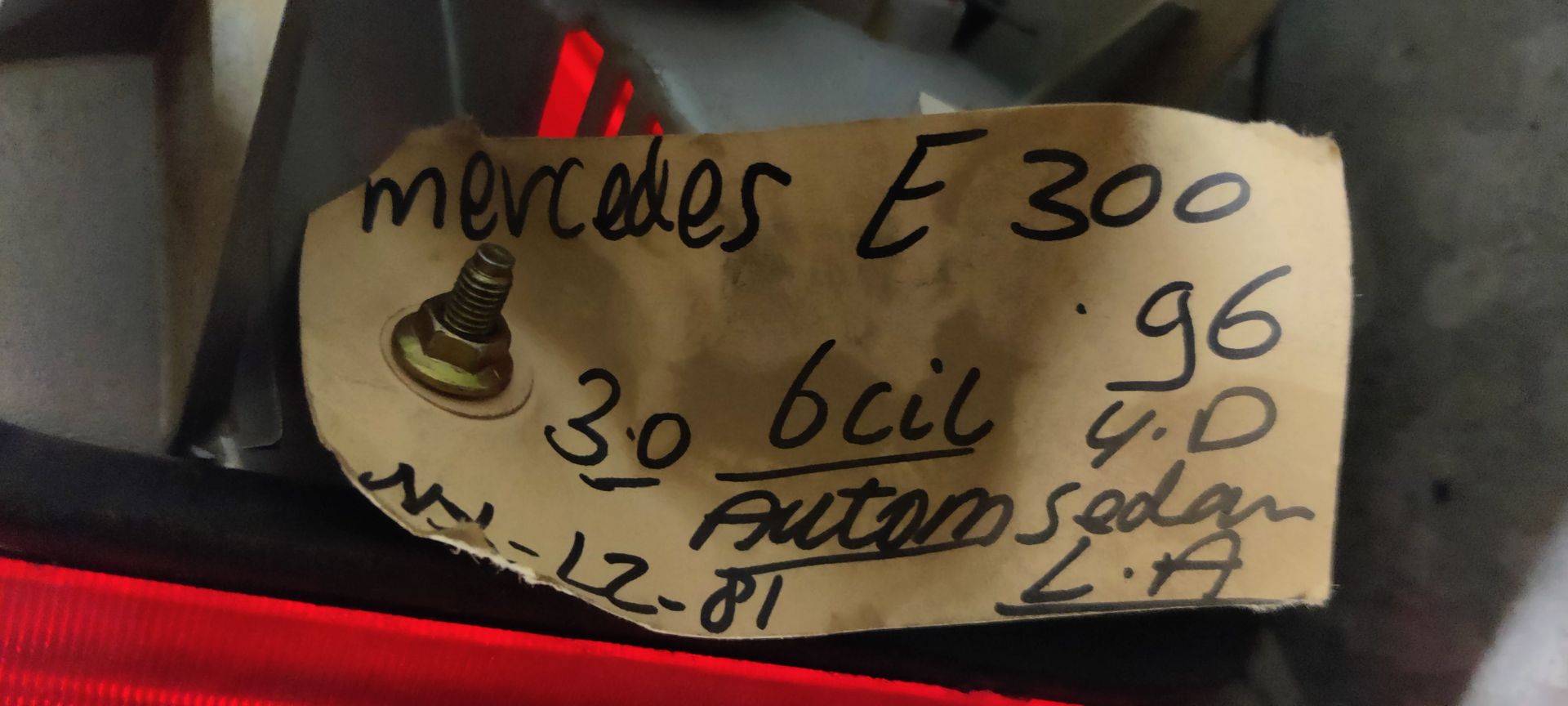 Een rechthoekige achterlichtunit voor een auto met horizontale rode en oranje lichtsecties op een grijs oppervlak.