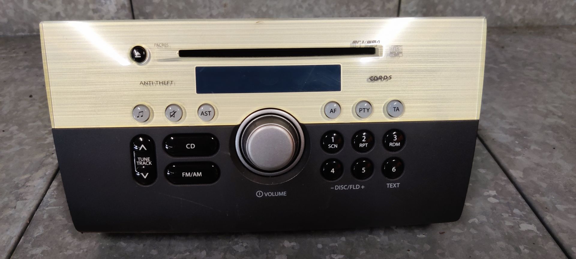 Suzuki Swift sport. Een tweekleurige autoradio en cd-speler met een beige bovengedeelte en een zwart bedieningspaneel aan de onderkant.